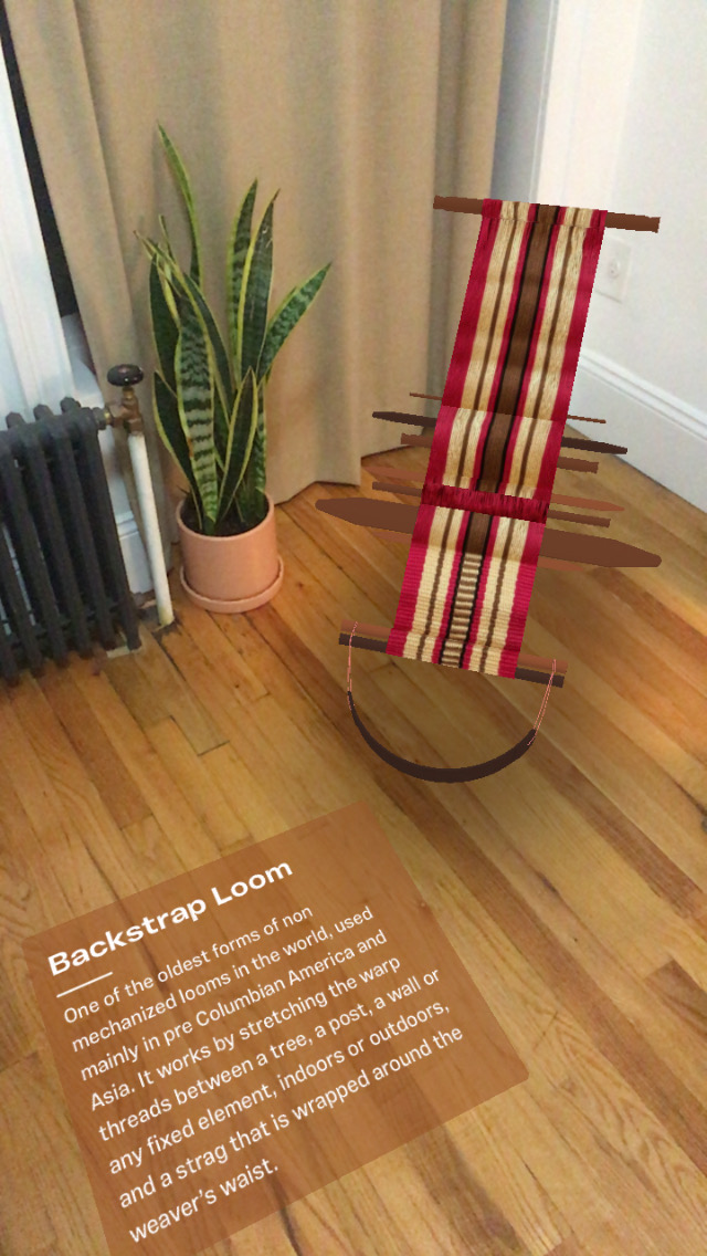 Video showing backstrap loom in augmented reality. The camera pans to the left showing a card on the floor with info about the loom.